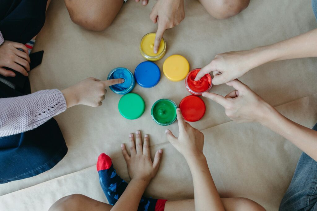 Children and parents dipping their fingers in paint bottles 