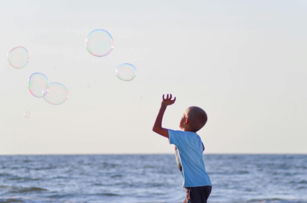bubble popping child in front of sea 