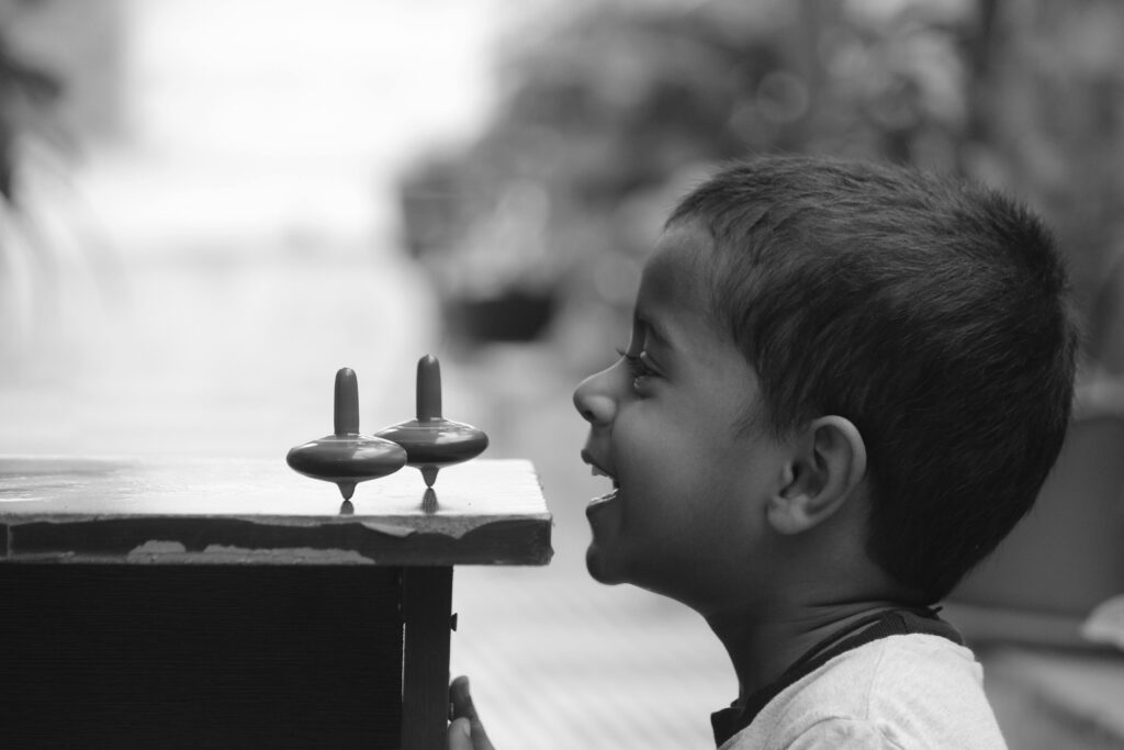 A 1-year-old toddler enjoying learning activities with spinning tops, captured in a black and white portrait.