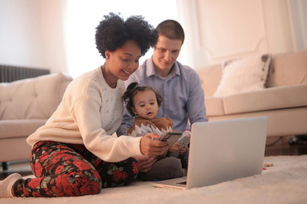 A joyful family of three enjoying togetherness while using a laptop indoors.