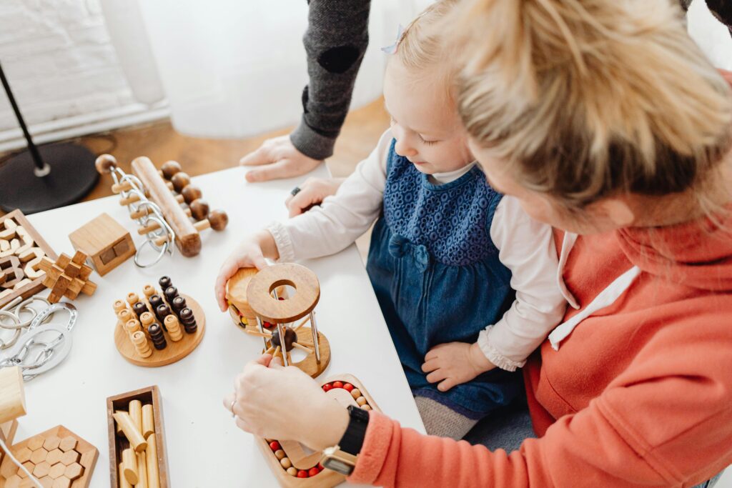 Mother and toddler enjoying creative toddler activities together with educational wooden toys during indoor playtime.