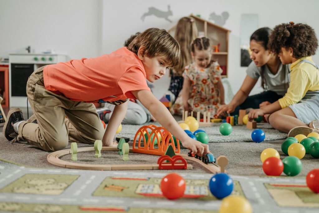Toddlers engaged in fun learning activities with toys and an educator in a kindergarten setting.