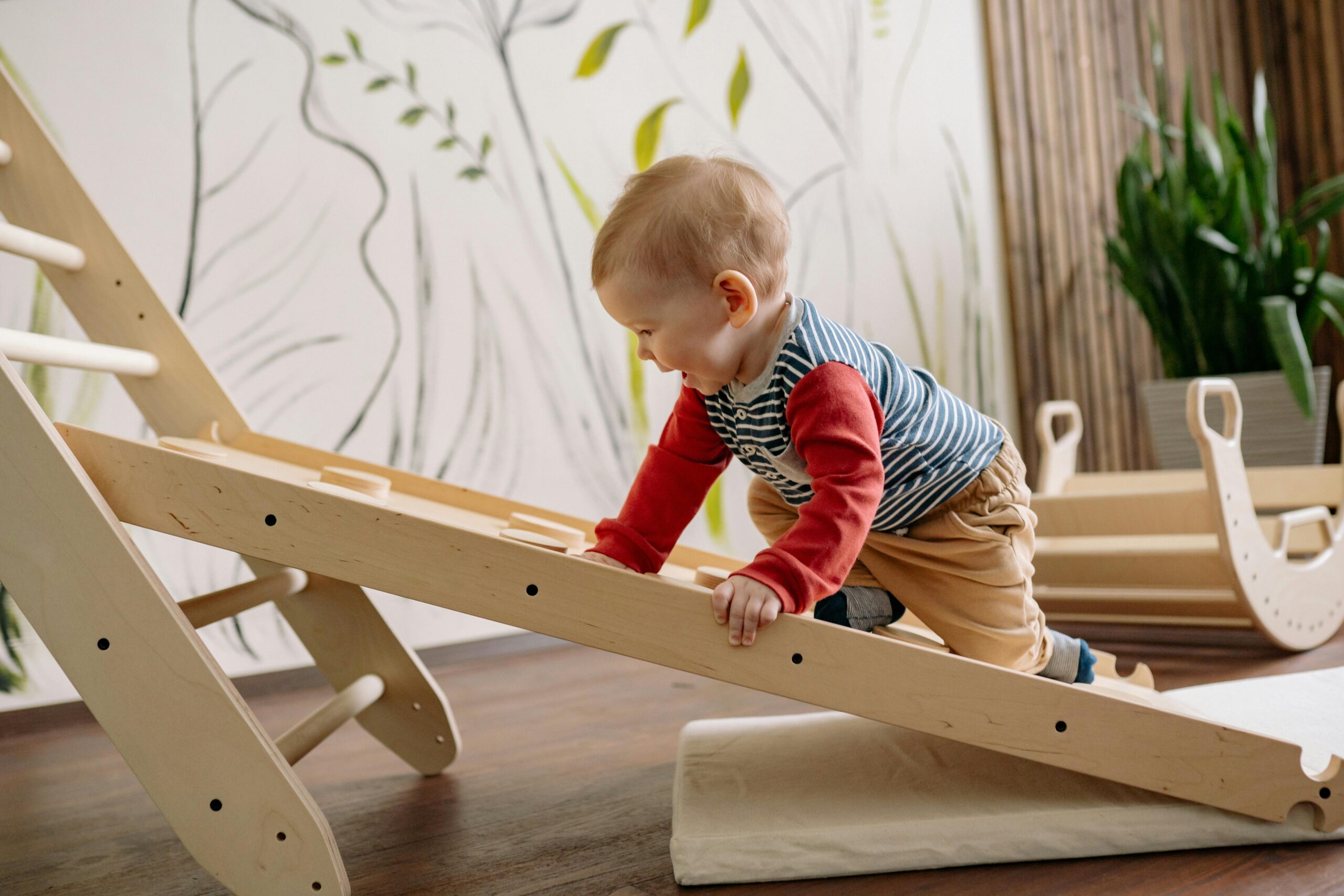 A young child enjoys climbing a wooden toy ladder indoors, promoting playtime and fun toddler activity for toddler development.
