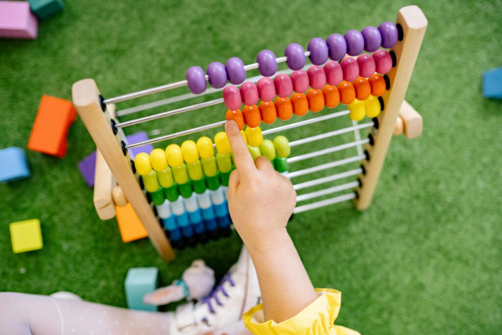 Child using a colorful wooden abacus, one of the best educational toys for toddlers"