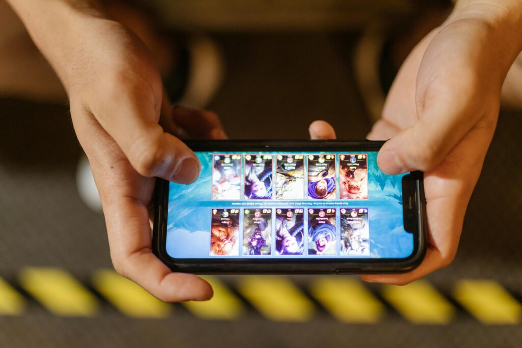 Close-up of hands playing a mobile game on a smartphone, showcasing the game's interface which is a kids search trends 2025.